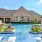 a swimming pool with chairs and a building in the background